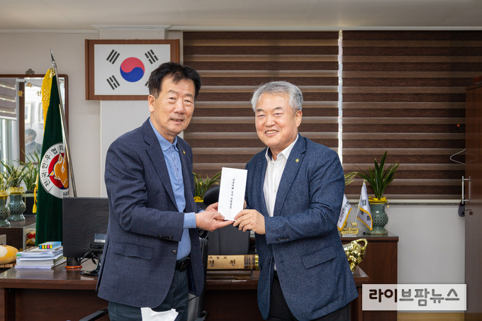 이재윤 한국종축개량협회장(사진 오른쪽)이 민경천 전국한우협회장에게 성금을 전달하고 있다.